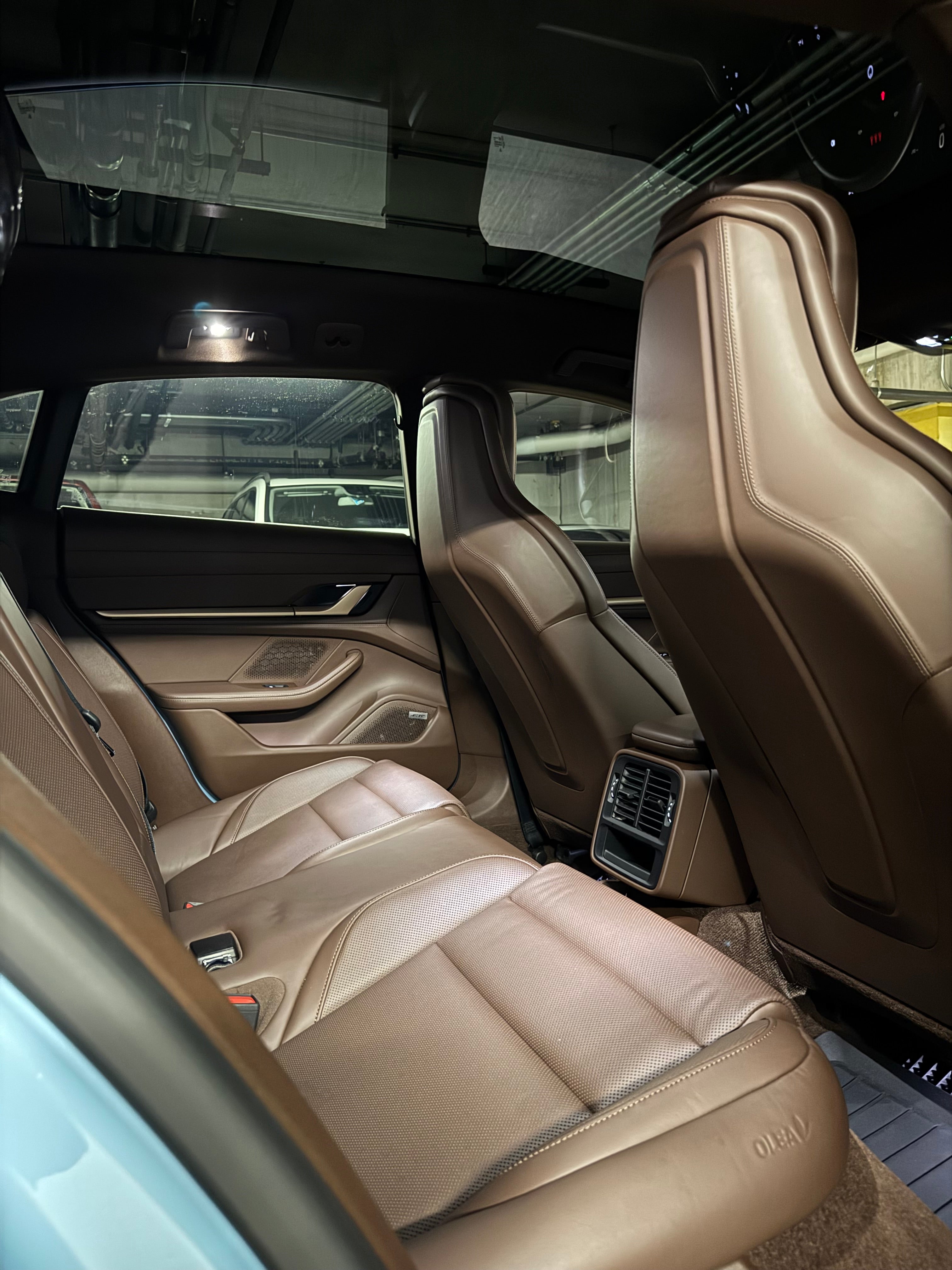 Porsche Taycan 4 interior view from the back seats to the sunroof, showcasing premium leather upholstery, spacious seating, and the sleek panoramic glass roof.