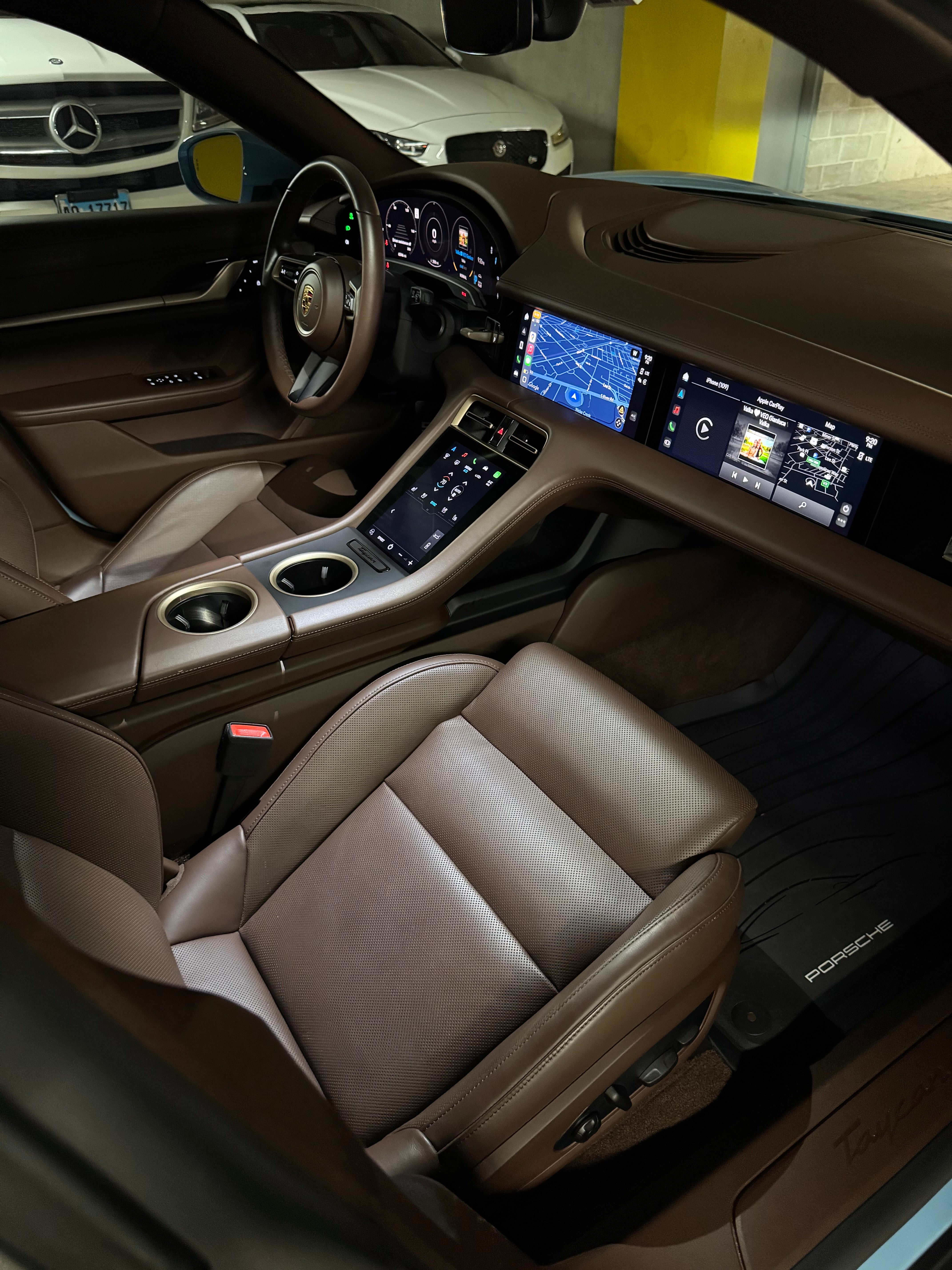 Porsche Taycan 4 interior view from the passenger seat to the dashboard, showcasing premium materials, sleek baby blue accents, advanced touchscreen display, and modern EV cockpit design.