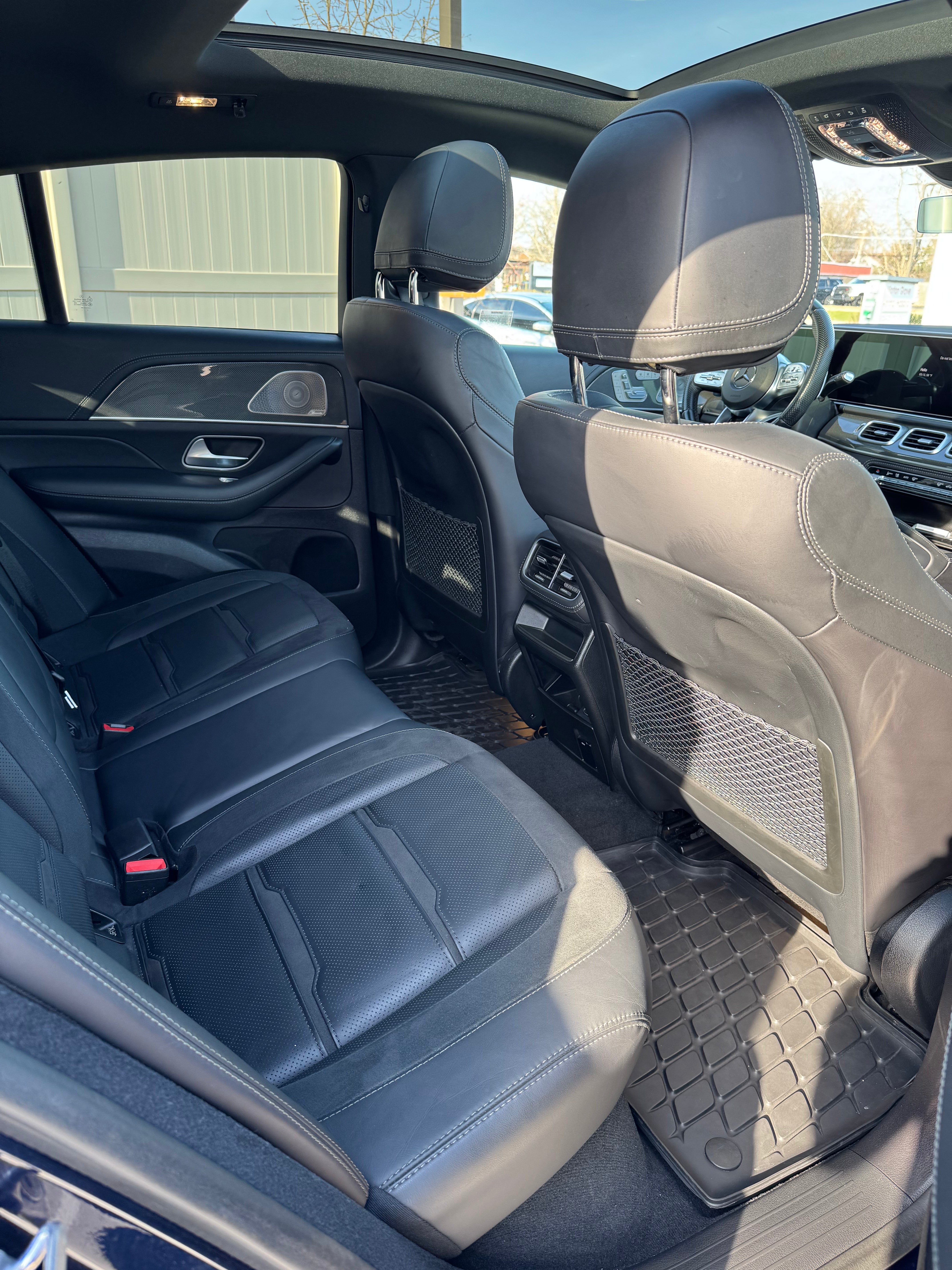 Mercedes-AMG GLE 53 back seats viewed from the passenger side door, highlighting premium leather upholstery, spacious interior, and a clear view of the panoramic sunroof and sophisticated dashboard.