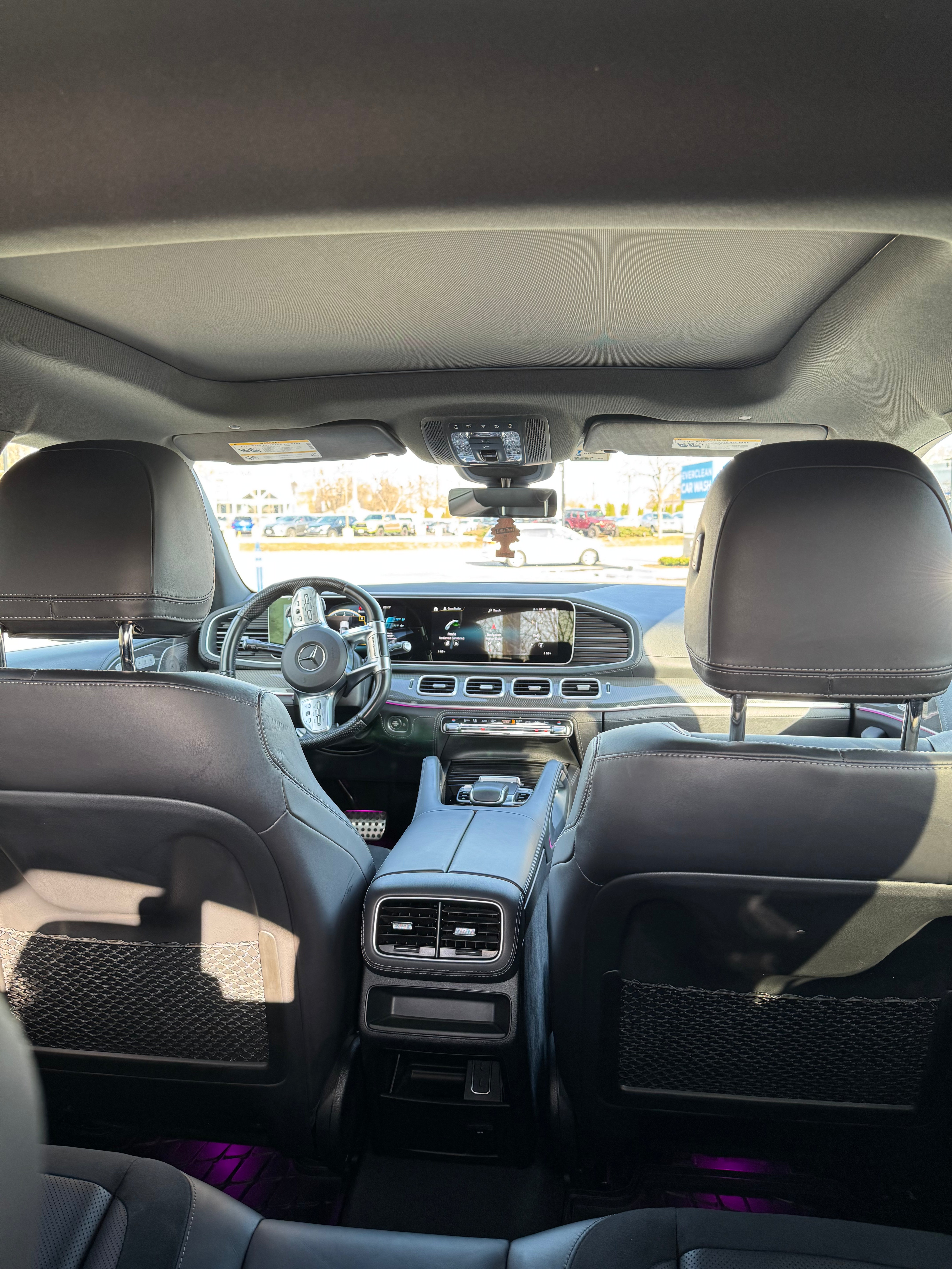 Mercedes-AMG GLE 53 back seat view looking to the front, showcasing the panoramic sunroof, sleek dashboard, and luxurious interior design.