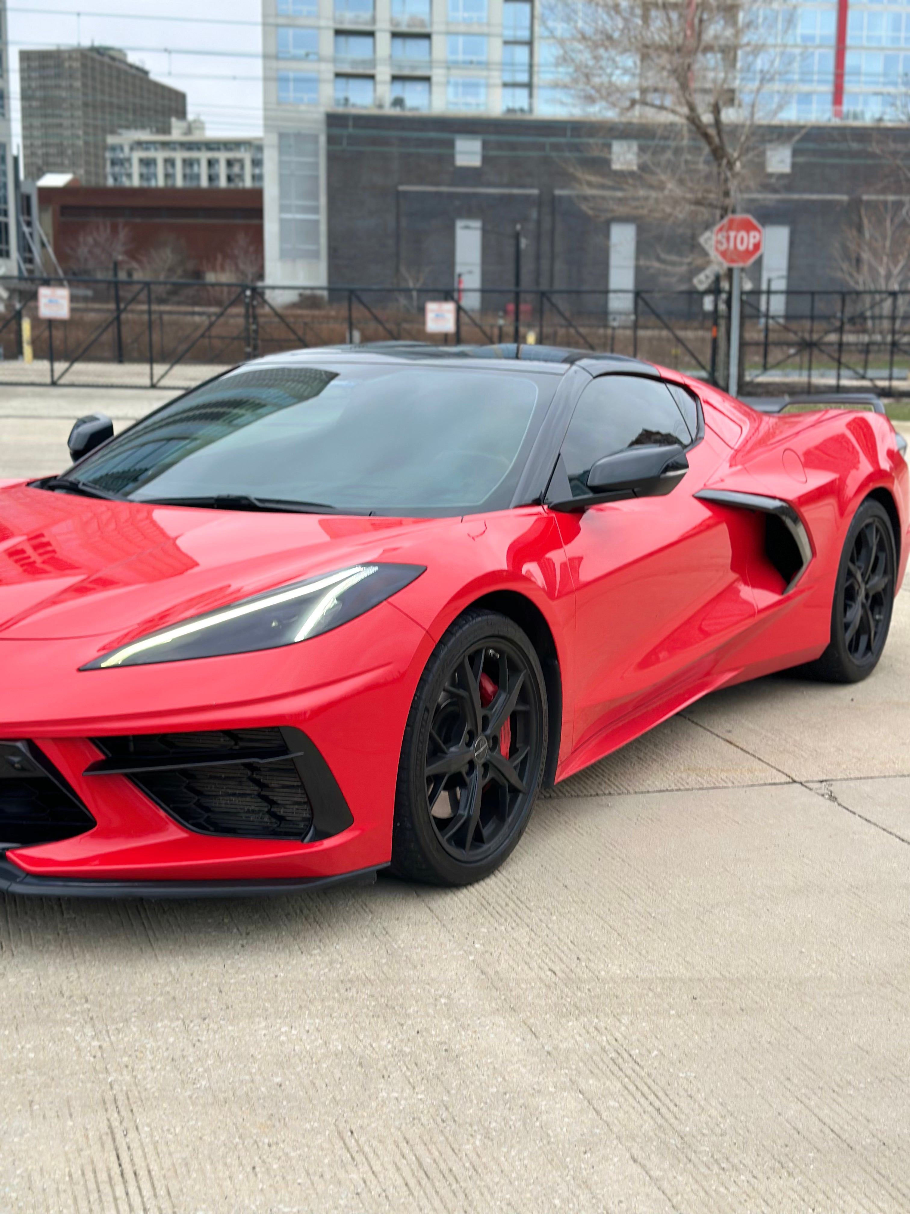 C8 Corvette front driver-side corner view showcasing bold red exterior, sleek headlights, and exotic sports car styling.