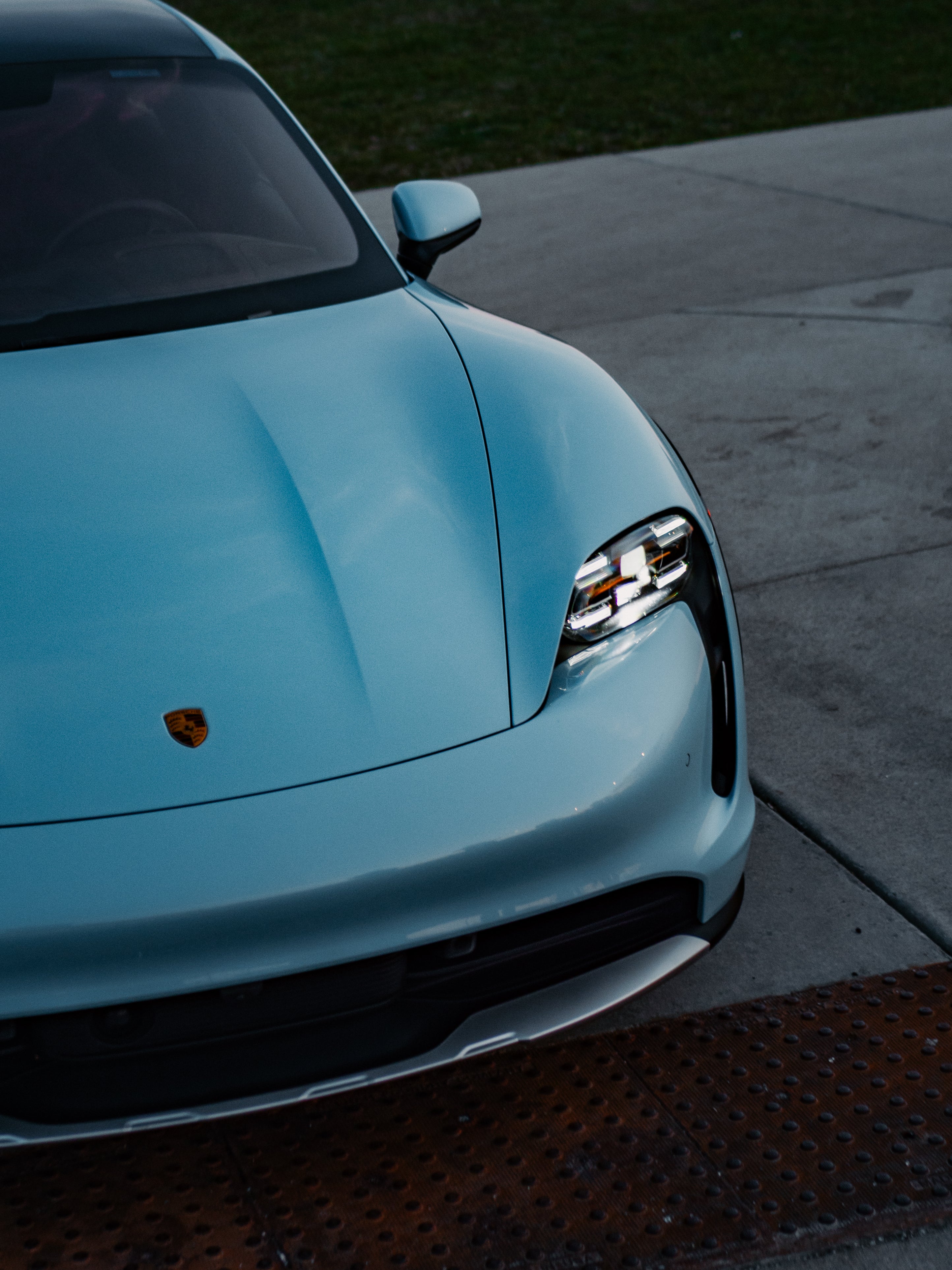 Porsche Taycan 4 front driver-side corner view showcasing bold baby blue exterior, sleek headlights, and electric sports car styling.
