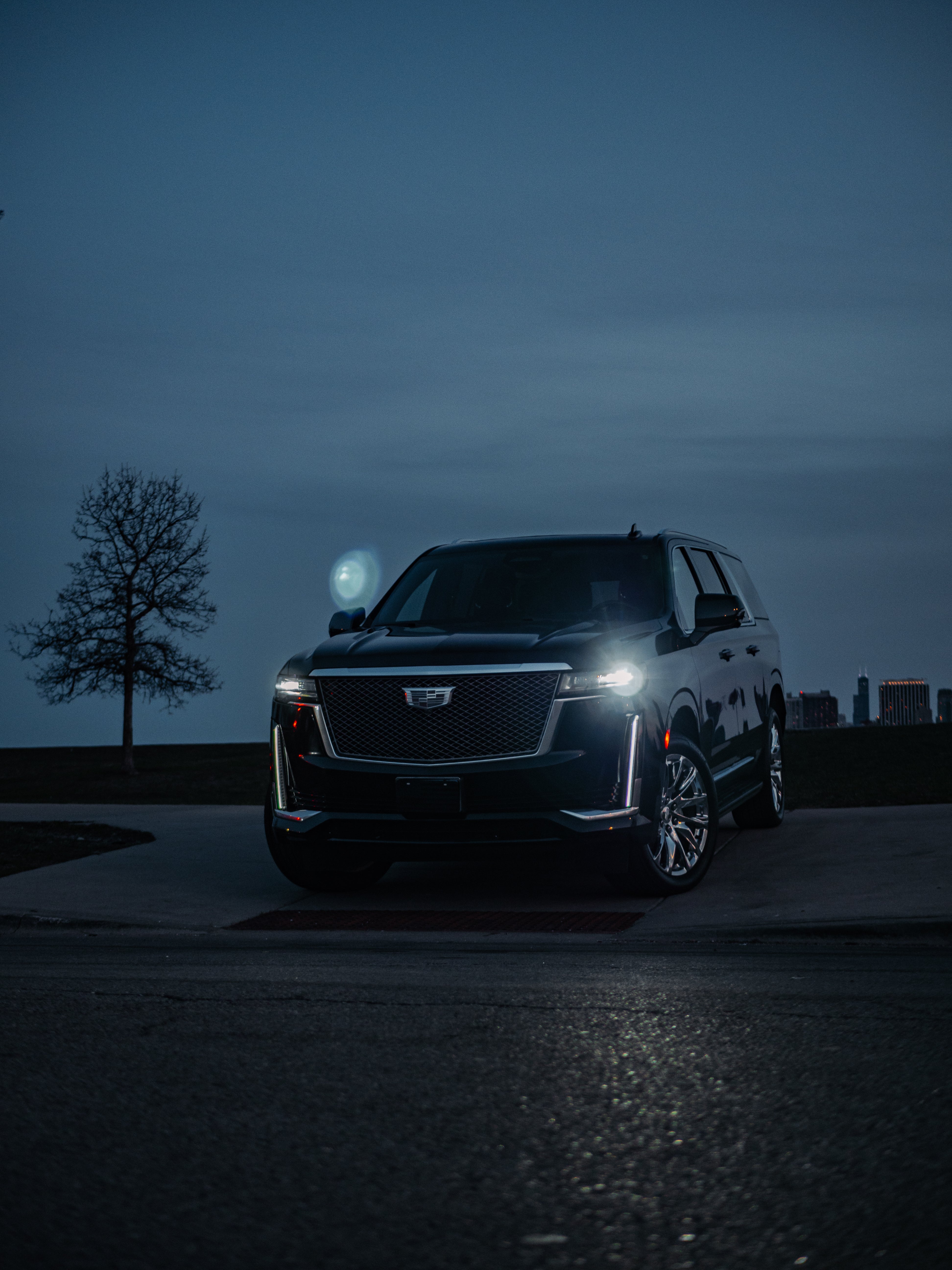 Cadillac Escalade front driver-side corner view showcasing bold black grille, sleek headlights, and luxury SUV styling.