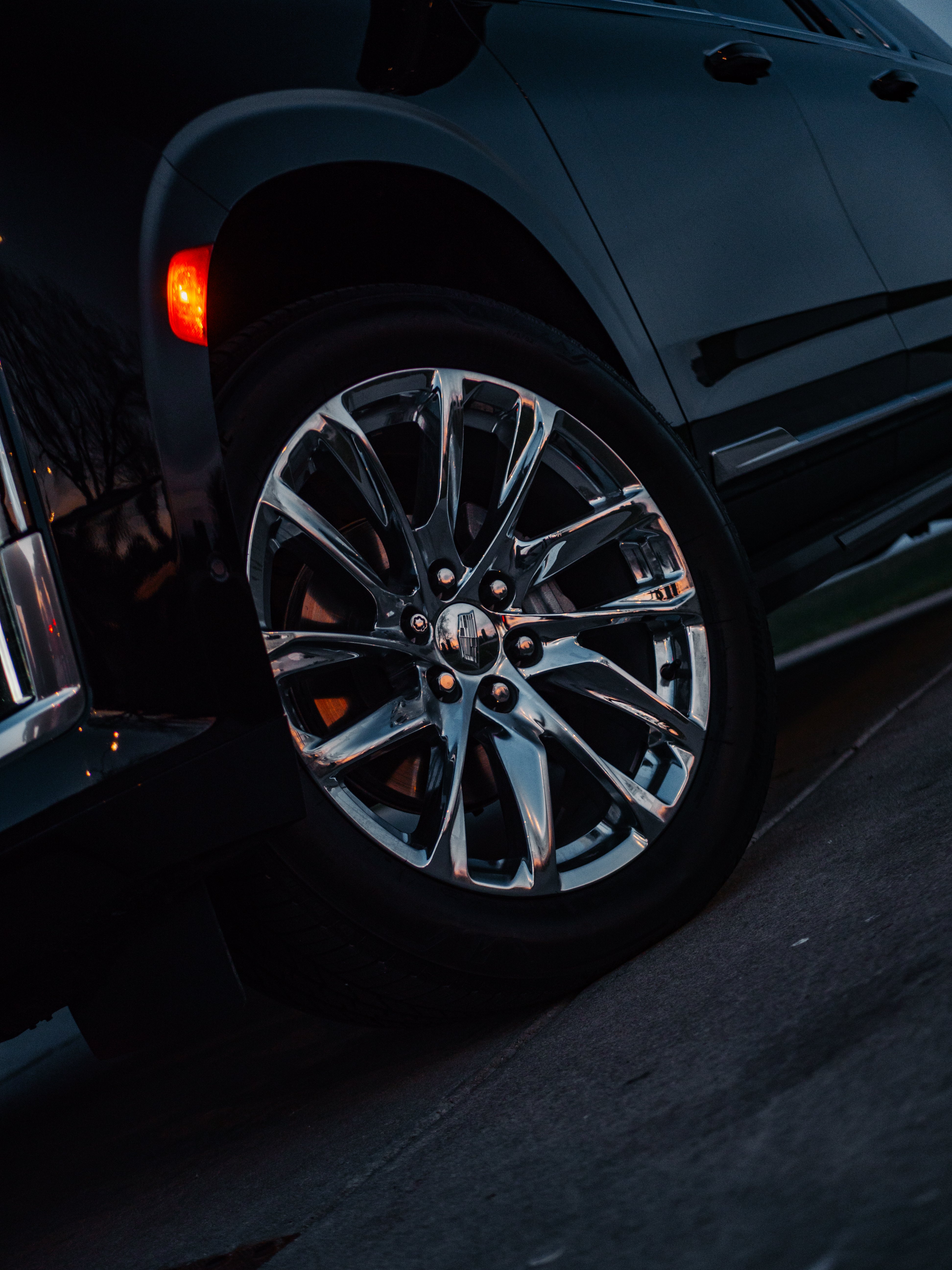 Cadillac Escalade close-up of premium black alloy wheels with bold design and luxury detailing, showcasing the SUV's sleek craftsmanship.