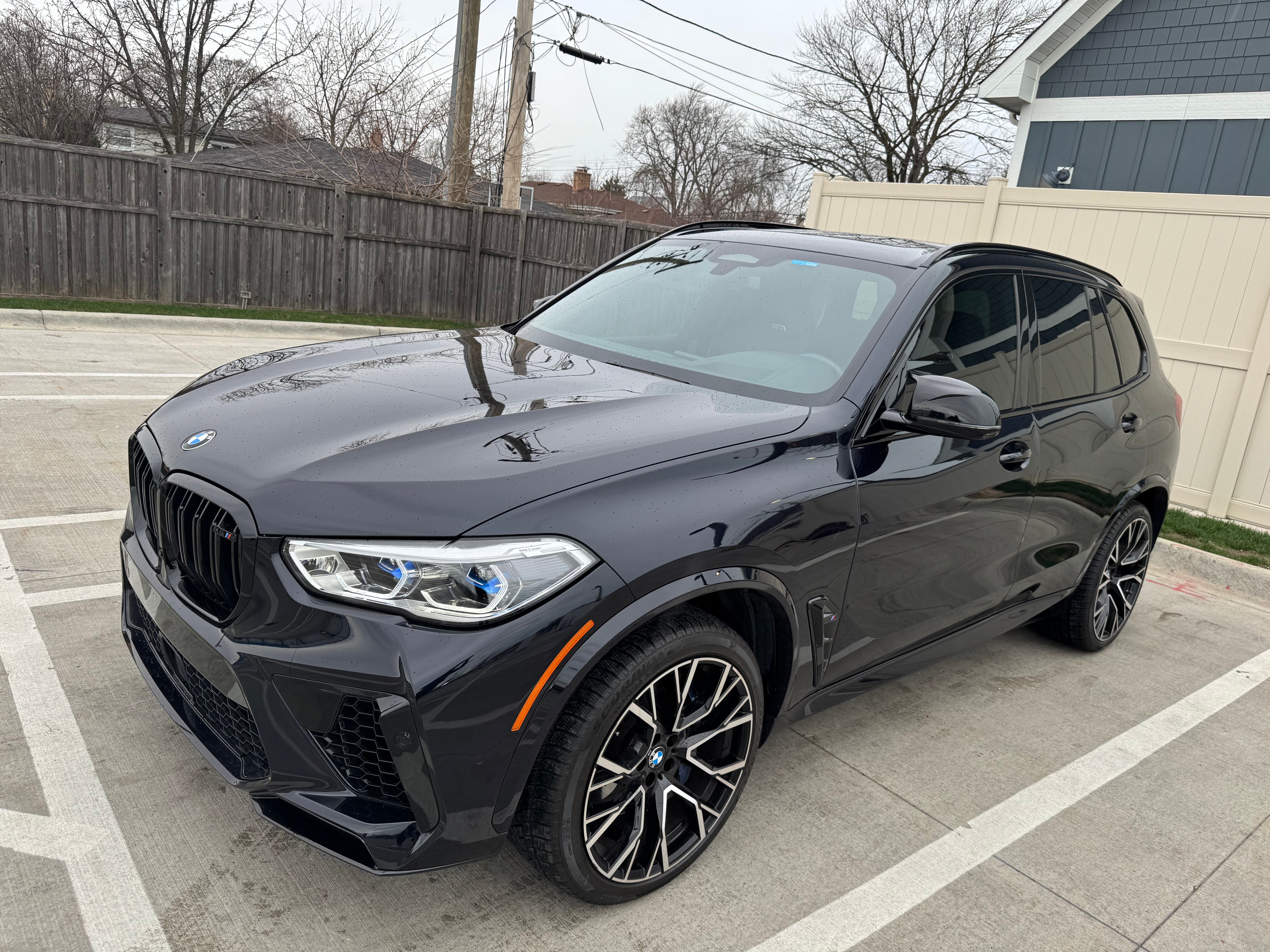 BMW X5M Competition corner front driver side view showcasing bold grille, sleek headlights, aerodynamic lines, and luxury SUV design.