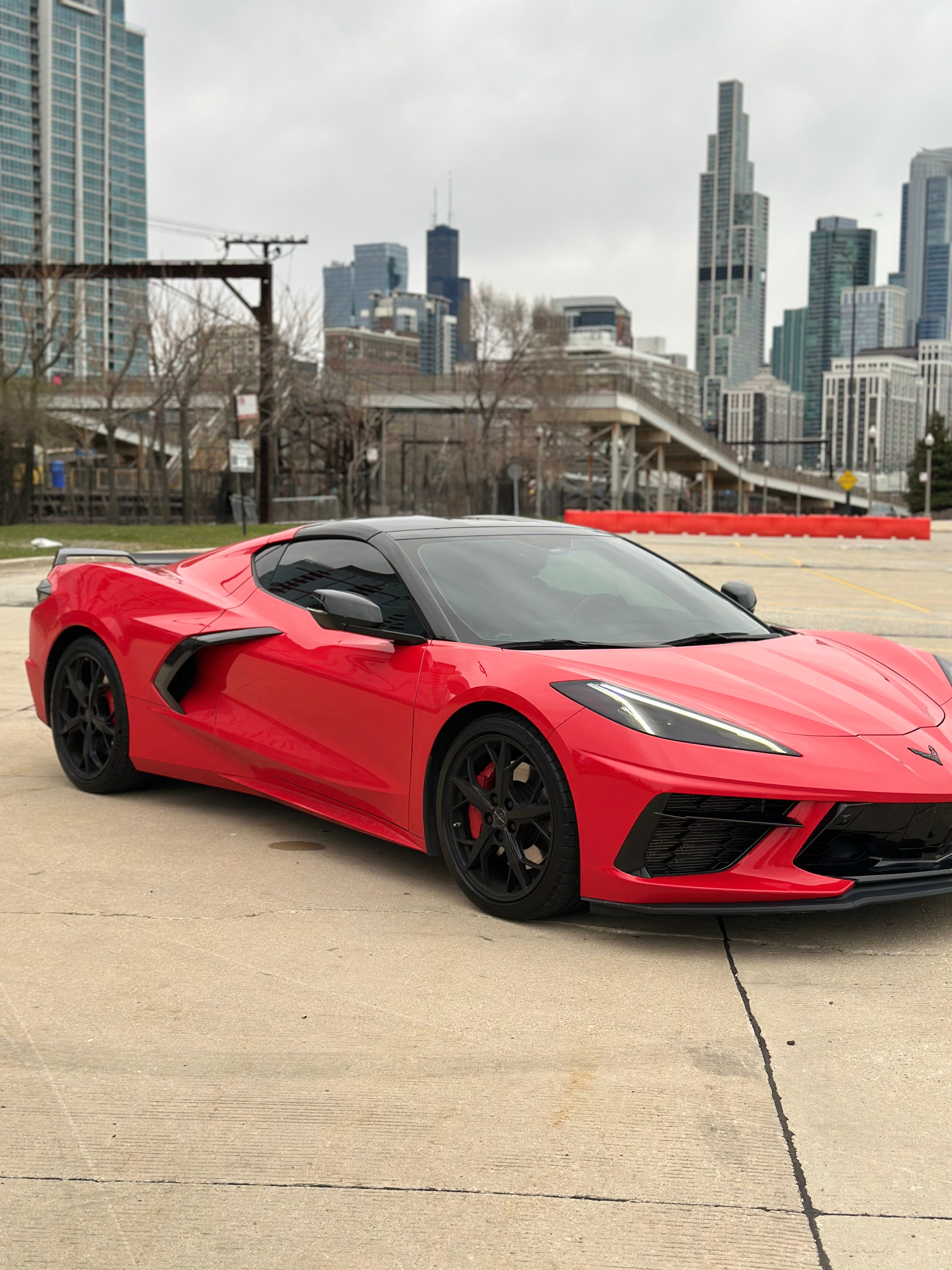 C8 Corvette passenger side profile showcasing sleek red exterior, sharp aerodynamic lines, and exotic car design.